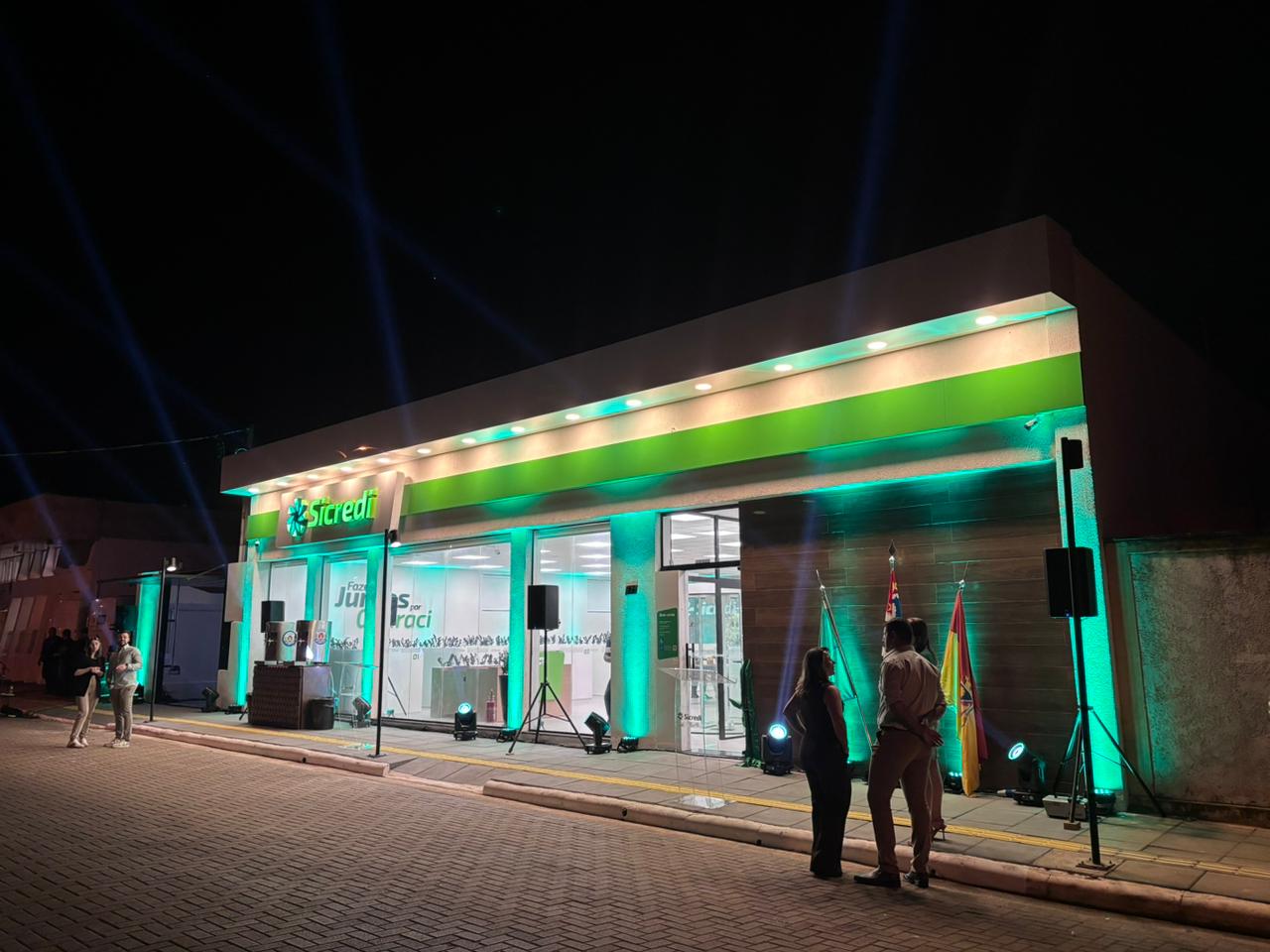 Fachada iluminada da agência Sicredi à noite